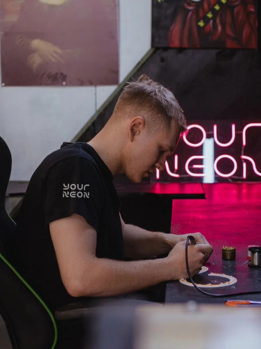 Мастер в мастерской в фирменной футболке YOUR NEON